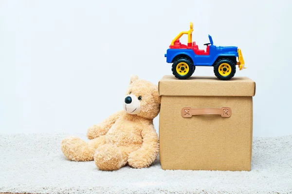 Brinquedo urso e carro com caixa têxtil marrom com alças e tampa — Fotografia de Stock