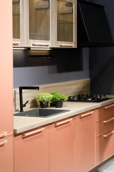 Contemporary kitchen with pink and wood cabinets. Selective focus.