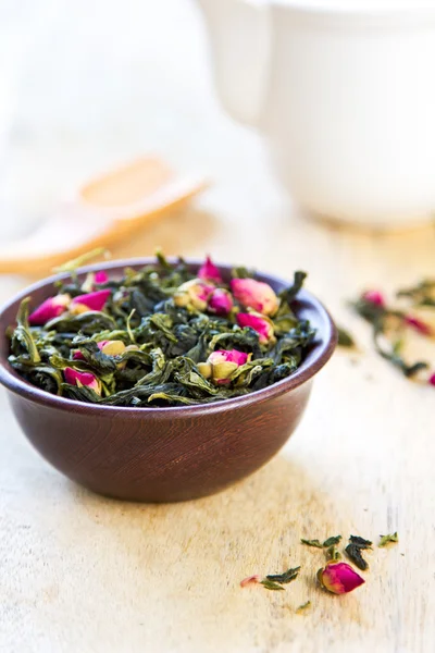 Grüne Teeblätter mit Rosenblüten — Stockfoto