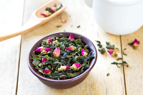 Grüne Teeblätter mit Rosenblüten — Stockfoto