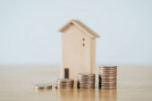 Dřevěný dům a skládání mincí na dřevěný stůl. úspora peněz na nákup domu, finanční plán koncepce úvěru domů.