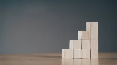 Pile of wooden cube block stack as stair step on wood table. Success, climbing to the top, Progression, business growth concept.