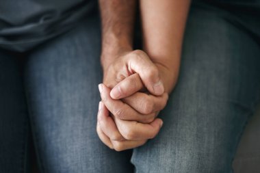 Kanepede oturan Asyalı olgun çifti yakından çek. Karı ve koca mutlu bir şekilde el ele tutuşuyorlar. Sevgi, güvenlik ve sigorta ailesi