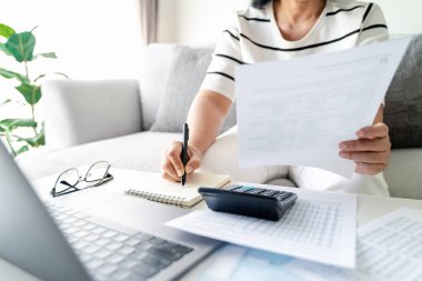 Kadın, yıllık vergisini hesap makinesi ve Bireysel Gelir Vergisi İade formuyla hesaplıyor. Vergi ve Bütçe Planlama Konsepti Ödeme Sezonu. 