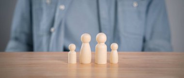 Adam ve tahta mandallı bebekler masanın üstünde. Planlama, aileyi kurtarma, sağlık ve sigorta, aile ruhsal sağlığı, uluslararası aile günü