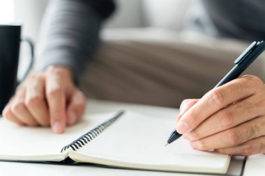 Solak adam masanın üzerine bir defter yazar.