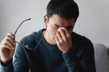 stressed man take off glasses massage eyes feel fatigue suffering from headache, exhausted man having eyestrain or astigmatism with overwork.