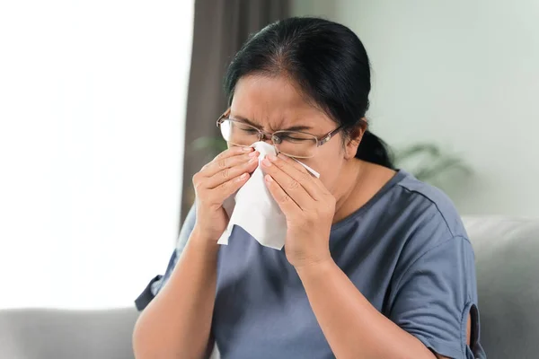 Cold sick woman got nose allergy cough or sneeze with tissue paper sitting on the sofa. Healthcare and medical concept