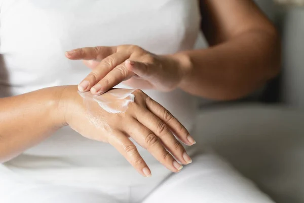 Woman applying body lotion moisturizer on her hands.