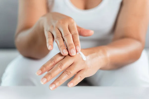 Woman applying body lotion moisturizer on her hands.