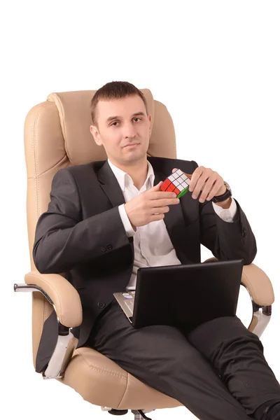 Mann sitzt auf einem Stuhl mit einem Rubik 's Cube — Stockfoto