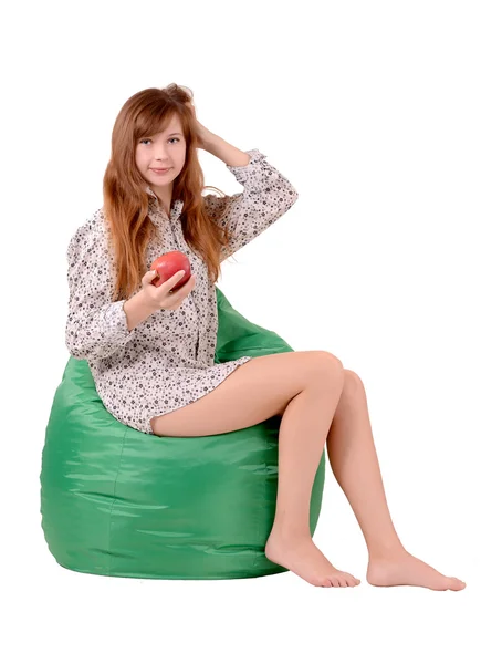 Dziewczyna z jabłkiem, siedząc na zielony pufe — Zdjęcie stockowe
