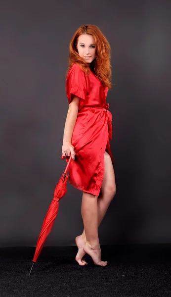 Barefoot red-haired girl in a red dressing gown — Stock Photo, Image