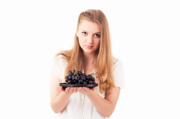 Chica con una rama de uvas en un plato — Foto de Stock