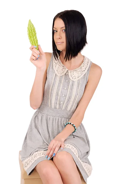 Flicka i en grå klänning som innehar en gurka — Stockfoto