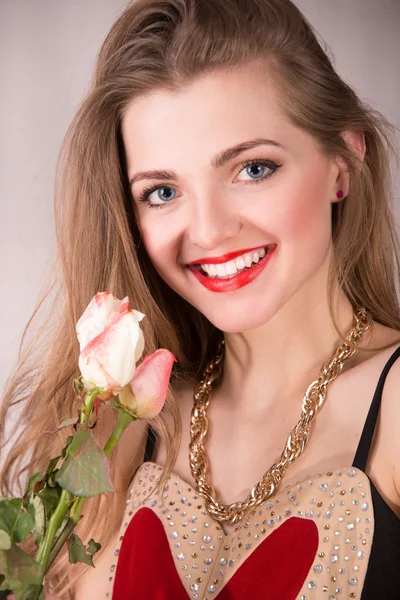 Vertikala porträtt av en ung kvinna håller en blomma och ler mot kameran — Stockfoto