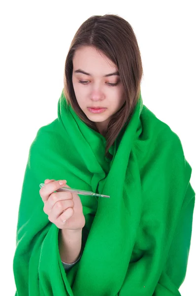 Нездоровая женщина, покрытая одеялом, держит в руке термометр. — стоковое фото