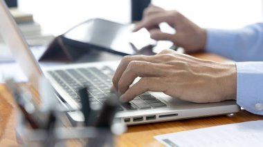 Mali veya muhasebe uzmanları şirketin gelir-gider grafiğini analiz etmek için dizüstü bilgisayar ve tablet kullanarak şirketin genel müdürüne ve ortağına, iş veri analizine sunum hazırlıyorlar..