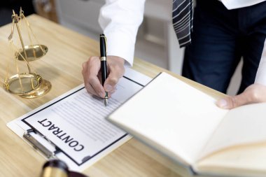 Avukatlar veya hakimler, yasal ve adil anlaşma, hukuki ahlak ve bütünlük, adalet terazisi, hukuki çekiç, dava ve hukuk hizmetleri çerçevesinde belgeleri imzalıyorlar..