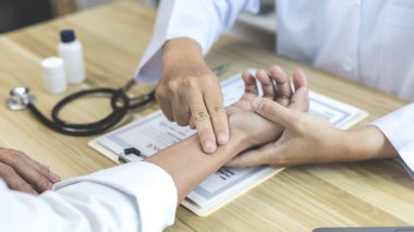 Tıbbi uzman, erkek bir hastanın bileğinin nabzını ölçerek hastane muayene odasında nabzını ölçer, doktor hasta sağlığını kontrol eder, ilk semptomları kontrol eder..