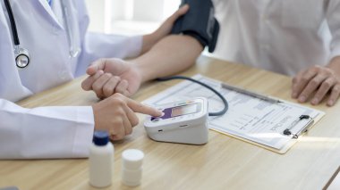 Erkek doktor, check-up, tıbbi tedavi ve sağlık konsepti için hastaneye gelen hastaların vücut basıncını ve nabzını ölçmek için kan basıncı monitörü kullanır..