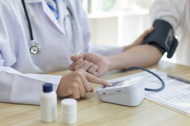 Erkek doktor, check-up, tıbbi tedavi ve sağlık konsepti için hastaneye gelen hastaların vücut basıncını ve nabzını ölçmek için kan basıncı monitörü kullanır..