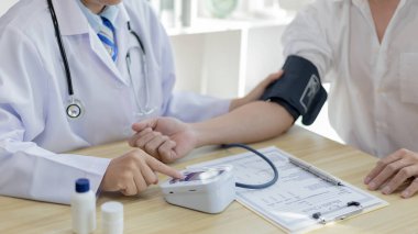 Erkek doktor, check-up, tıbbi tedavi ve sağlık konsepti için hastaneye gelen hastaların vücut basıncını ve nabzını ölçmek için kan basıncı monitörü kullanır..