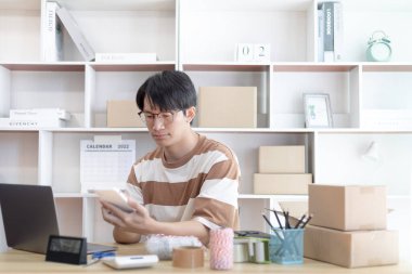 Çevrimiçi ürün satan genç adam telefonda bir müşteriden sipariş almak için konuşuyordu ve listeyi bir not defterine yazdı. Gençler için yeni bir iş, çevrimiçi, küçük işletme sahibi satışı..