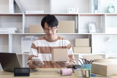 İnternette ürün satan adam telefonda ya da sohbet ederek bir müşteri ve listeden sipariş alıyordu. İnternetten alışveriş yapan KOBİ girişimcisi, paketleme kutusu, çevrimiçi satış, serbest çalışma..