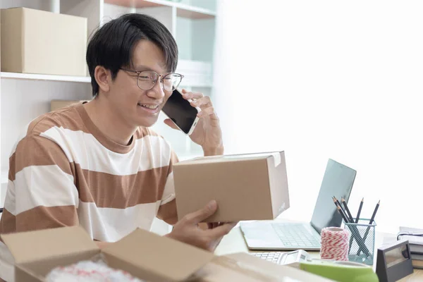 Asian man is taking online orders from a phone and chatting with customers to confirm their order, Selling products online or doing freelance work at home, Working at home and owning businesses.