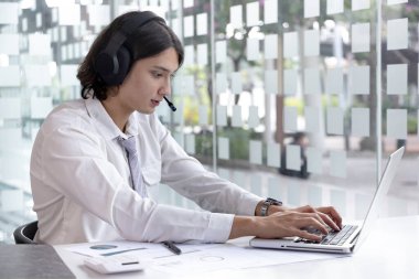 İş adamı video sohbetleri yoluyla arkadaşlarını ve müdürünü karşılıyor ve iletişim ve iş konuşmaları için kulaklık kullanıyor, İnternet iletişimi, Yeni Normal, VDO Çağrısı, İnternet öğrenimi.