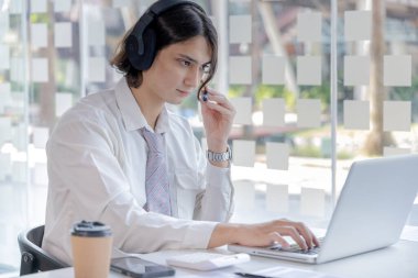 İş adamı video sohbetleri yoluyla arkadaşlarını ve müdürünü karşılıyor ve iletişim ve iş konuşmaları için kulaklık kullanıyor, İnternet iletişimi, Yeni Normal, VDO Çağrısı, İnternet öğrenimi.