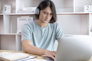 Genç Asyalı adam, yüzünde gülümseme, internet iletişimi, evde kalmak, yeni normal, VDO çağrısı, sosyal uzaklık, internet öğrenimi olan canlı bir videoda arkadaşlarını ve öğretmenlerini selamlıyor..