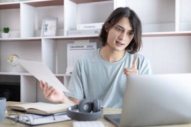 Genç Asyalı erkekler video sohbetleri yoluyla arkadaşlarını ve öğretmenlerini selamlıyor ve onları neşeli ifadelerle karşılıyor, İnternet iletişimi, Evde kal, Yeni Normal, VDO Çağrısı, Sosyal Mesafe, İnternet öğrenimi.