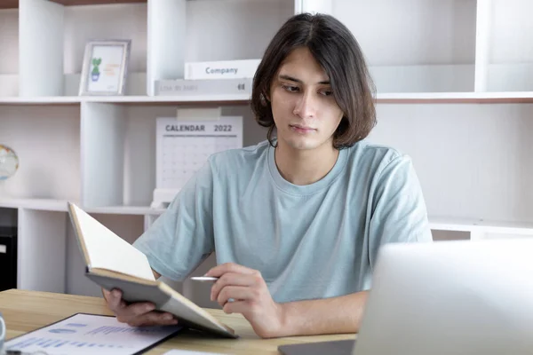 Hombre Asiático Tomando Notas Cuaderno Mientras Estudia Línea Ordenador Portátil — Foto de Stock