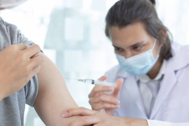 Doktor aşısı, yeni virüs türlerine karşı aşı elinde şırınga, insanlara antivirüs aşısı, Covid-19, klinikte ya da hastanede erkek hastaya aşı yapan doktor..