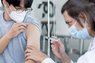 Doktor aşısı, yeni virüs türlerine karşı aşı elinde şırınga, insanlara antivirüs aşısı, Covid-19, klinikte ya da hastanede erkek hastaya aşı yapan doktor..
