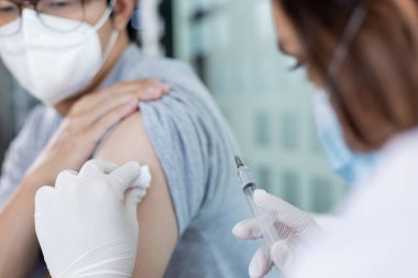 Doktor aşısı, yeni virüs türlerine karşı aşı elinde şırınga, insanlara antivirüs aşısı, Covid-19, klinikte ya da hastanede erkek hastaya aşı yapan doktor..