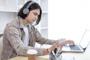 Genç öğrenci ödevini yapıyor ve sömestr tatilinde laptopunda canlı olarak yayınlanıyor, Evde kal, Yeni Normal, Mesafe Öğrenme, Sosyal Mesafe Öğrenme, Çevrimiçi, Şehirlerarası İletişim.