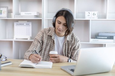 Genç öğrenci ödevini yapıyor ve sömestr tatilinde laptopunda canlı olarak yayınlanıyor, Evde kal, Yeni Normal, Mesafe Öğrenme, Sosyal Mesafe Öğrenme, Çevrimiçi, Şehirlerarası İletişim.