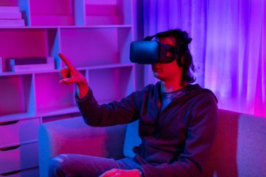 Sanal gerçeklik gözlüğü takan adam heyecan verici bir 3 boyutlu oyun oynuyor, Bluetooth Uzaktan Kumanda, VR, Gelecek Oyunları, Gadget, Teknoloji, Kırmızı ve Mavi arka plan, VR oyun konsepti.