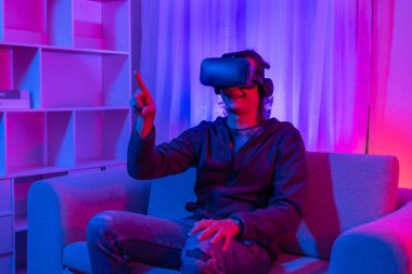 Sanal gerçeklik gözlüğü takan adam heyecan verici bir 3 boyutlu oyun oynuyor, Bluetooth Uzaktan Kumanda, VR, Gelecek Oyunları, Gadget, Teknoloji, Kırmızı ve Mavi arka plan, VR oyun konsepti.