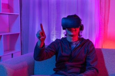 Sanal gerçeklik gözlüğü takan adam heyecan verici bir 3 boyutlu oyun oynuyor, Bluetooth Uzaktan Kumanda, VR, Gelecek Oyunları, Gadget, Teknoloji, Kırmızı ve Mavi arka plan, VR oyun konsepti.