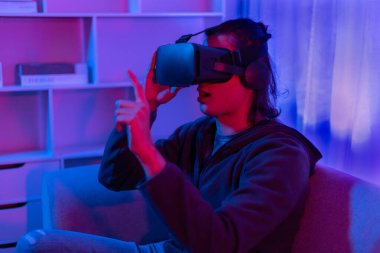 Sanal gerçeklik gözlüğü takan adam heyecan verici bir 3 boyutlu oyun oynuyor, Bluetooth Uzaktan Kumanda, VR, Gelecek Oyunları, Gadget, Teknoloji, Kırmızı ve Mavi arka plan, VR oyun konsepti.