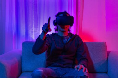 Sanal gerçeklik gözlüğü takan adam heyecan verici bir 3 boyutlu oyun oynuyor, Bluetooth Uzaktan Kumanda, VR, Gelecek Oyunları, Gadget, Teknoloji, Kırmızı ve Mavi arka plan, VR oyun konsepti.