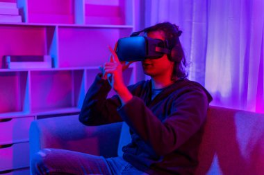 Sanal gerçeklik gözlüğü takan adam heyecan verici bir 3 boyutlu oyun oynuyor, Bluetooth Uzaktan Kumanda, VR, Gelecek Oyunları, Gadget, Teknoloji, Kırmızı ve Mavi arka plan, VR oyun konsepti.