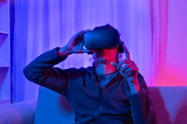 Sanal gerçeklik gözlüğü takan adam heyecan verici bir 3 boyutlu oyun oynuyor, Bluetooth Uzaktan Kumanda, VR, Gelecek Oyunları, Gadget, Teknoloji, Kırmızı ve Mavi arka plan, VR oyun konsepti.