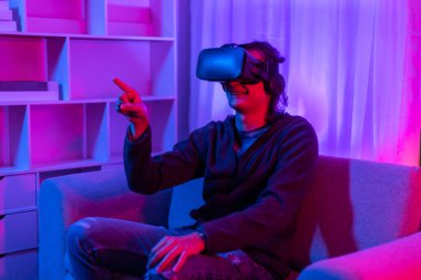 Sanal gerçeklik gözlüğü takan adam heyecan verici bir 3 boyutlu oyun oynuyor, Bluetooth Uzaktan Kumanda, VR, Gelecek Oyunları, Gadget, Teknoloji, Kırmızı ve Mavi arka plan, VR oyun konsepti.