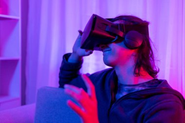 Sanal gerçeklik gözlüğü takan adam heyecan verici bir 3 boyutlu oyun oynuyor, Bluetooth Uzaktan Kumanda, VR, Gelecek Oyunları, Gadget, Teknoloji, Kırmızı ve Mavi arka plan, VR oyun konsepti.