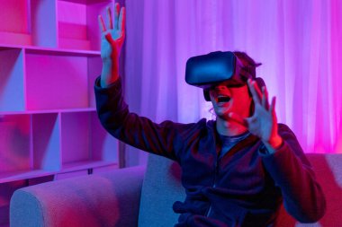 Sanal gerçeklik gözlüğü takan adam heyecan verici bir 3 boyutlu oyun oynuyor, Bluetooth Uzaktan Kumanda, VR, Gelecek Oyunları, Gadget, Teknoloji, Kırmızı ve Mavi arka plan, VR oyun konsepti.